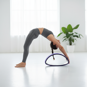 Woman doing backbend on purple yoga wheel
